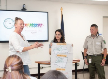 A person holding a poster with a person standing in front of a group of people